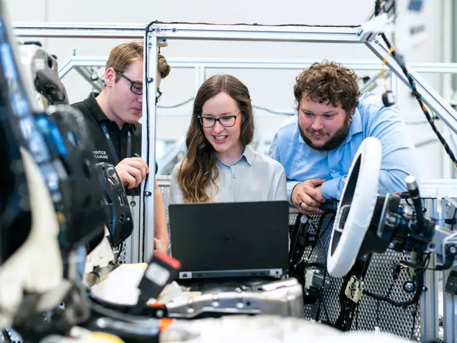 Administrative team working together at a laptop in a technical facility